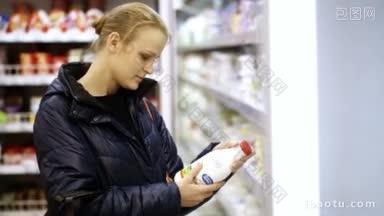 在超市的乳制品区，一名年轻女子正在把一瓶牛奶放入购物篮中
